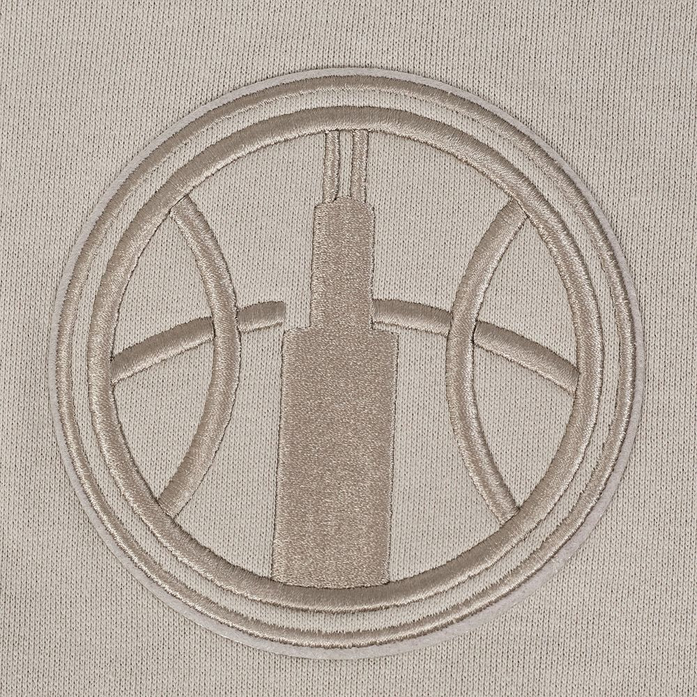 Embroidered design of a building in a circle on a beige fabric background