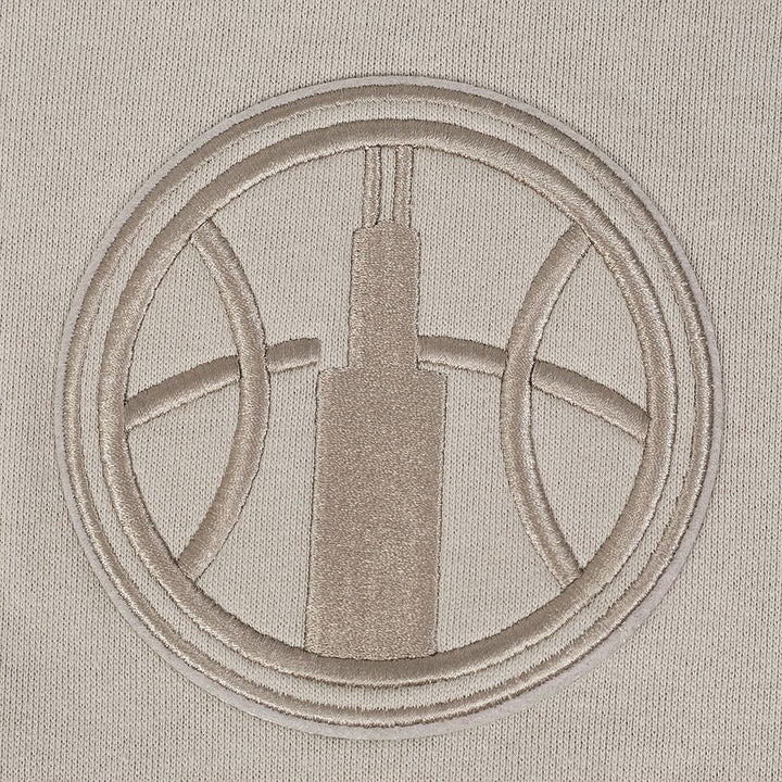 Embroidered design of a building in a circle on a beige fabric background